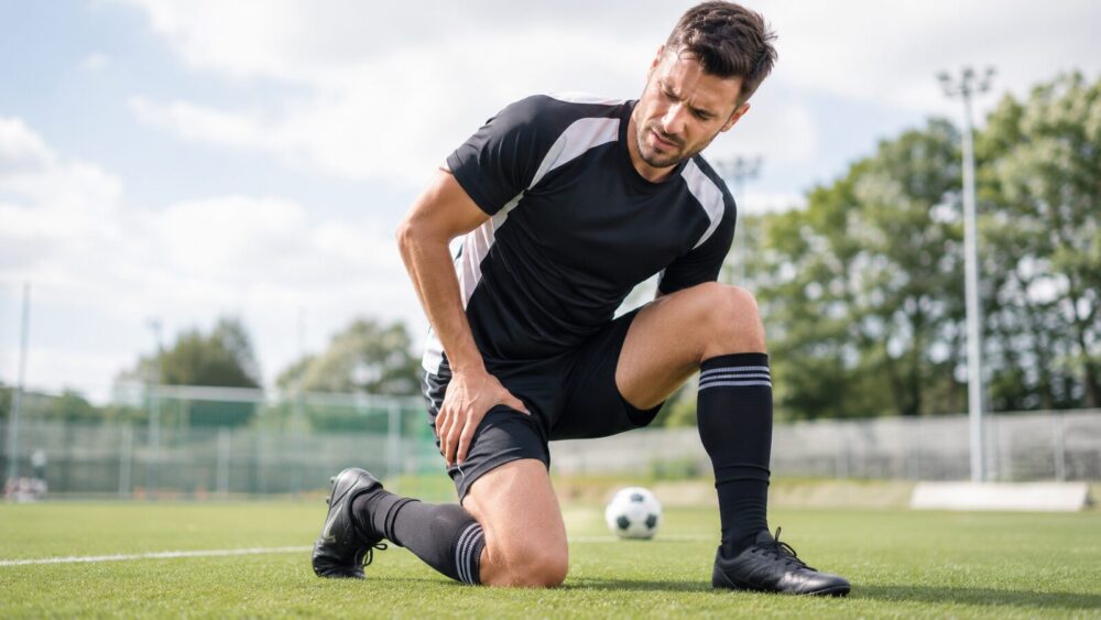 Voetballer houdt zijn lies vast door een blessure op het veld – Spine Clinics