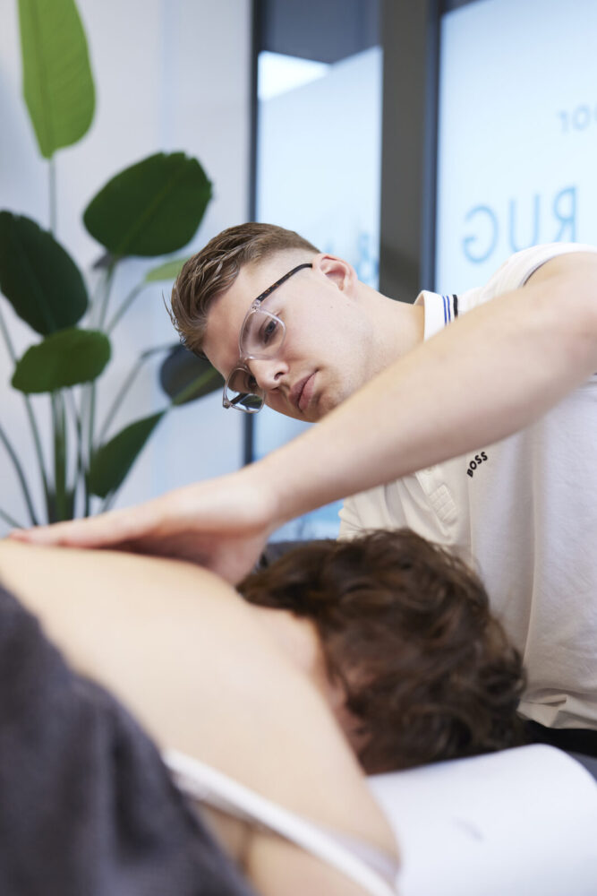 Behandelaar behandelt de nek en schouder van een patiënt – Spine Clinics