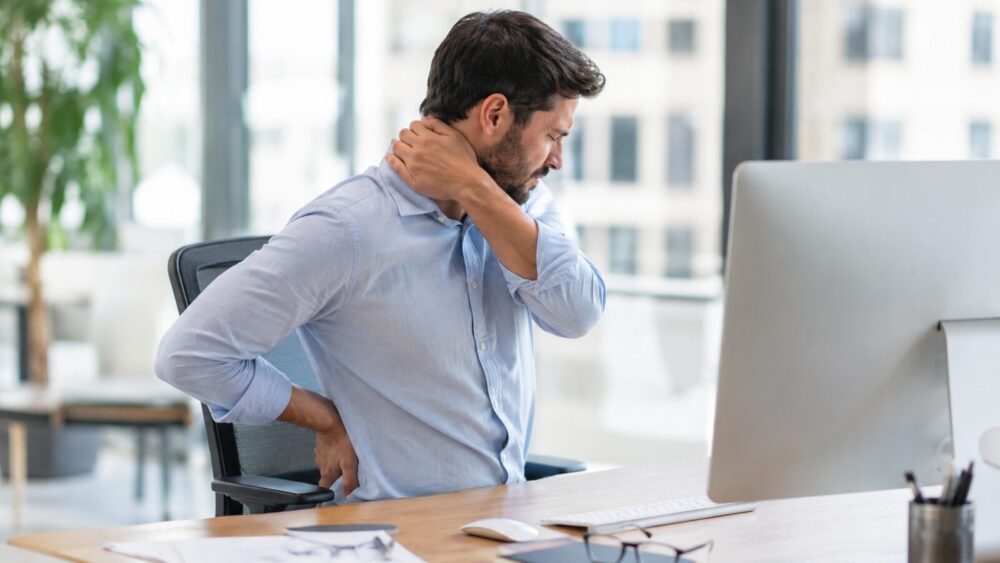 Kantoorwerker met nek- en rugklachten door langdurig zitten achter het bureau